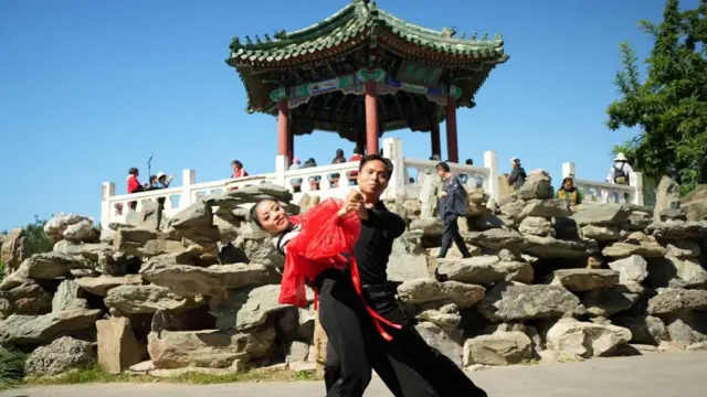 Dançarinos no Ritan Park, em frente a um templo tradicional chinês.