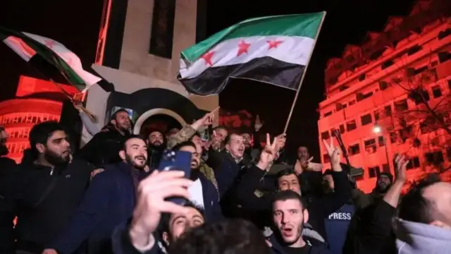 Homens em uma rua a noite parecem celebrar.