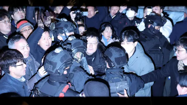 Des membres de l'armée se frayent un chemin à travers la foule devant l'Assemblée nationale à Séoul, aux premières heures du 4 décembre, après que le président sud-coréen Yoon Suk Yeol a déclaré la loi martiale.