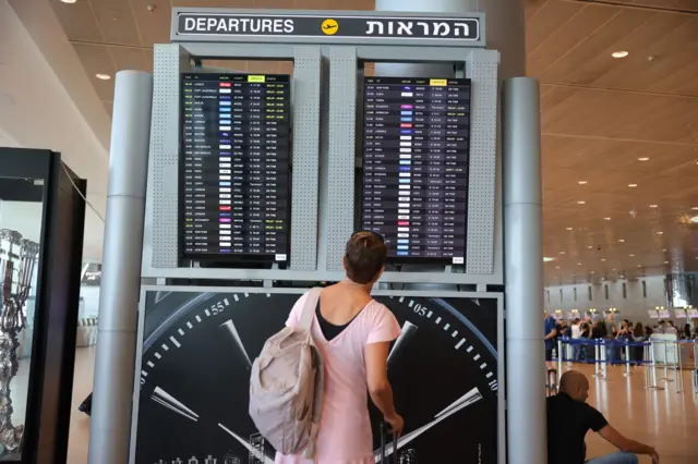 Mulher olha tela com voos no Aeroporto Ben Gurion, o principal de Israel