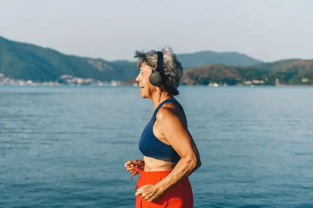 Mulher de idade avançada fazendo esporte na rua, com o mar ao fundo