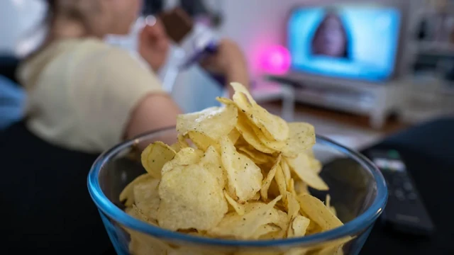 Tijela com batata frita em frente a TV