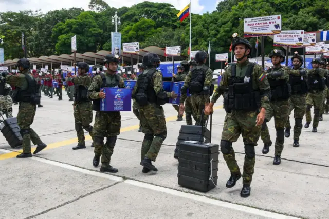 Militares venezuelanos com máquinas de votação e urnas