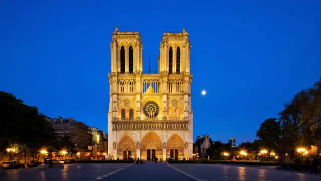 Visão frontal da catedral, que aparece iluminada em início de noite