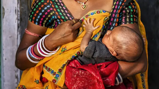 Mulher amamentando o filho recém-nascido