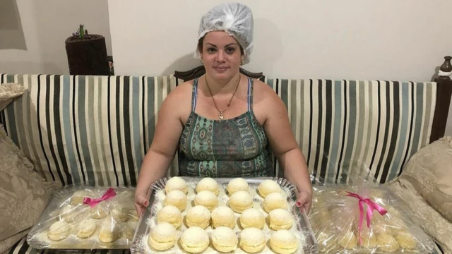 Patrícia sentada no sofá, com tabuleiro cheio de pãezinhos no colo