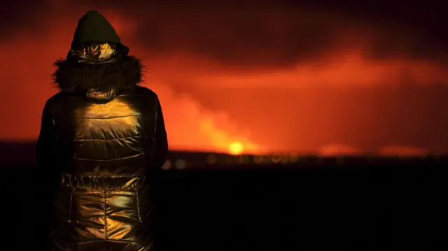 Mulher observa lava do vulcão