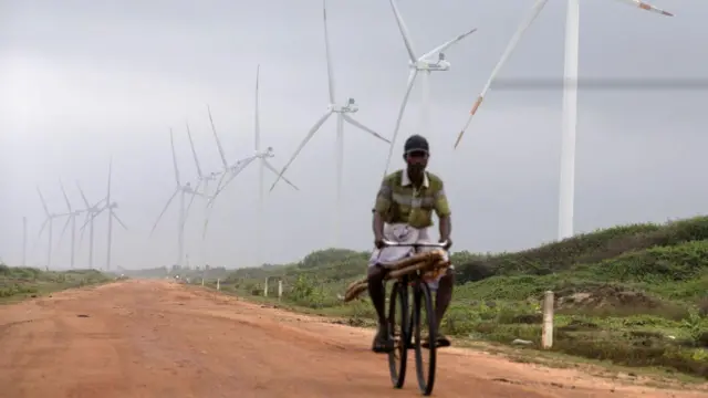 Um homem passa de bicicleta por um parque eólico no Sri Lanka, país que está se voltando cada vez mais para as energias renováveis ​​após uma crise econômica causada em parte pelos altos custos de energia