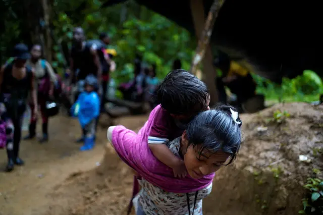 Uma migrante carrega uma criança enquanto atravessa a selva de Darién, entre o Panamá e a Colômbia, a caminho dos Estados Unidos, em 9 de julho de 2023. REUTERS/Adri Salido 