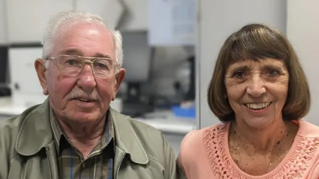 Casal em escritório sorrindo para câmera