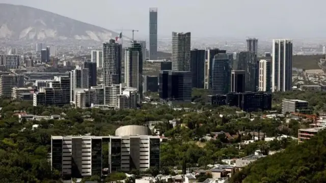 Imagem de uma cidade grande, cheia de prédios, com uma montanha no fundo ao lado esquerdo