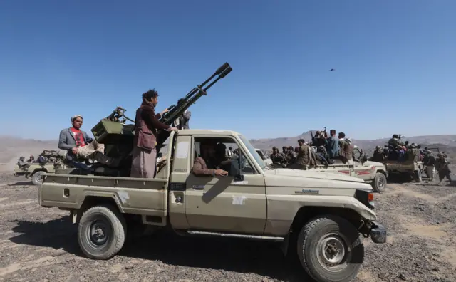 Homens houthis armados em cima de caminhonete 