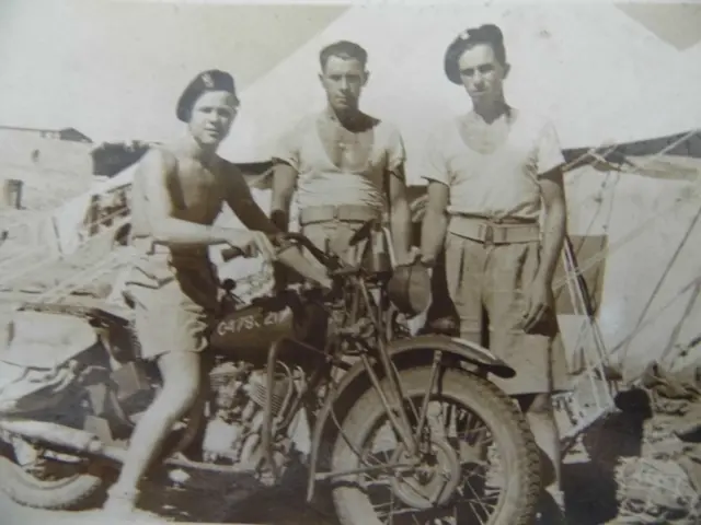 Andrzej Gasior, sem camisa, sentado em sua motocicleta ao lado de outros dois soldados 