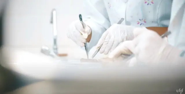 Alunos de medicina da UFJF dissecando - a foto tem foco nas mãos e não mostra a peça humana