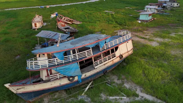 Foto mostra um barco em um gramado, onde antes havia um lago.