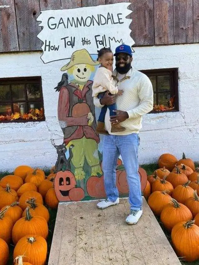 Eric Taylor com a filha de dois anos no colo em meio a abóboras