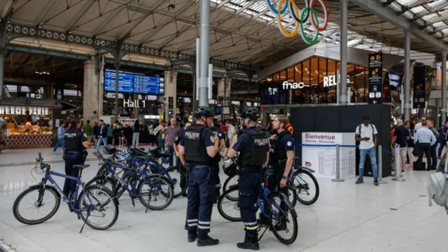 Policiais com uniforme azul-escuro conversam em torno de bicicletas em estação de trem de Paris