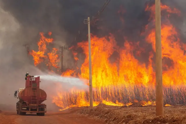 Caminhão de bombeiro jogando água em fogo no campo