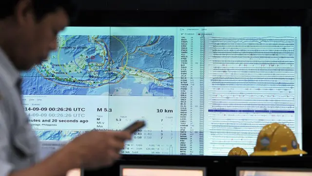 Funcionário indonésio verifica em seu telefone se há um alerta de terremoto e tsunami por SMS durante um exercício de tsunami no Oceano Índico