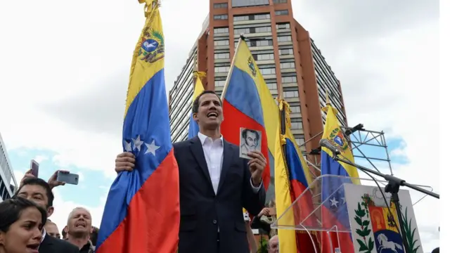 O líder oposicionista Juan Guaidó, que segura bandeira da venezueka, se proclamou o novo presidente interino do país durante protestos de milhares contra o governo de Nicolás Maduro