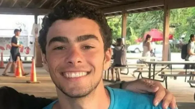 Foto de um homem branco sorrindo com sobrancelhas grossas