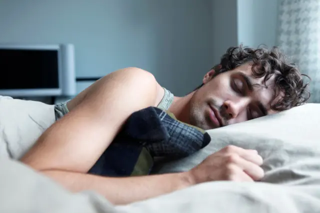 Homem jovem dormindo em uma cama