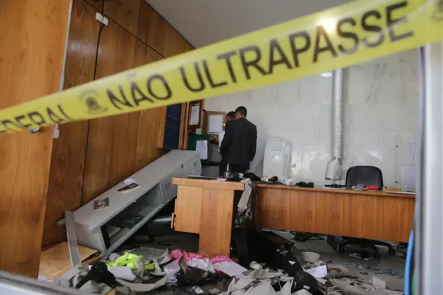 Homens observam estragos no Palácio do Planalto após invasão de manifestantes no dia 8 e janeiro de 2023