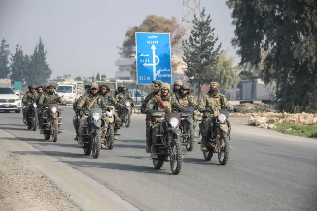 Combatentes rebeldes em motocicletas avançando em direção a Homs, na Síria