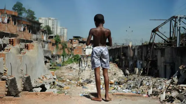 Menino descalço em comunidade de baixa renda