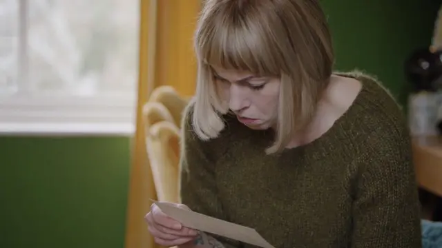 Helen Mort lendo algo em um pedaço de papel