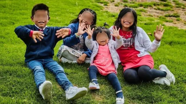 Os quatro irmãos sentados em um gramado sorrindo para foto compartilhada pelo ICBF