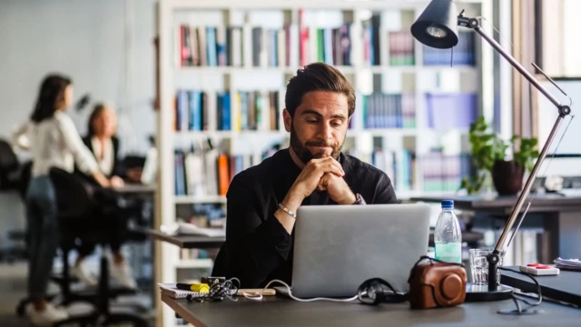 Homem com expressão de desapontado em frente a notebook