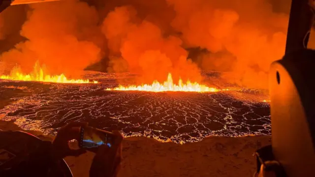 Pessoas tiram foto de lava num helicóptero 