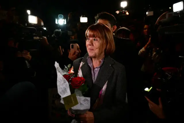 Gisèle Pelicot sorrindo e segurando um buquê de rosas vermelhas ao sair do tribunal de Avignon