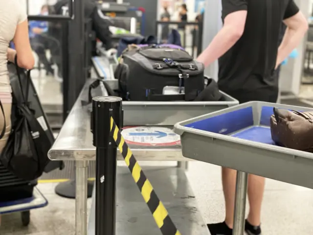 Foto mostra pessoa passando malas em um detector de metal de aeroporto