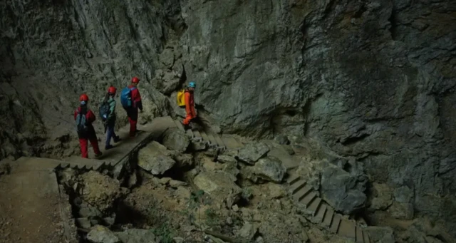 Grupo de quatro pessoas dentro de uma caverna, descendo escadas