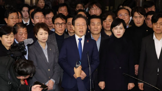 Le chef du principal parti d'opposition, le Parti démocrate, Lee Jae-myung (C), annonce sa position à l'Assemblée nationale à Séoul, le 4 décembre 2024, peu après qu'une session plénière d'urgence de l'Assemblée nationale a adopté une résolution exhortant le président à retirer la loi martiale.