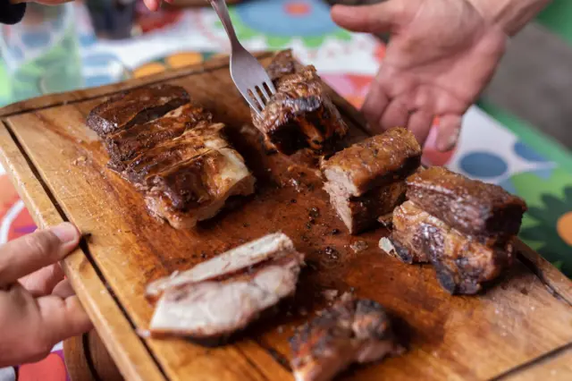 Carne assada sendo oferecida em cima de tábua