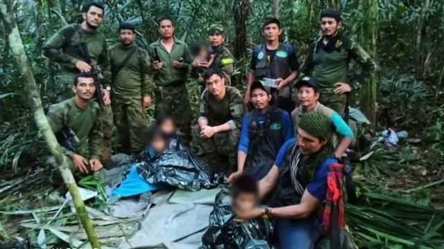 Foto publicada das crianças, com os rostos borrados, com parte da equipe de resgate na selva