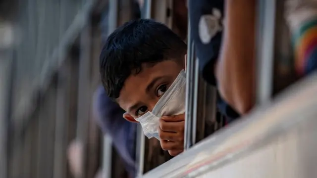 Um menino usando uma máscara espia pela janela de um ônibus prestes a deixar Manila antes de um lockdown em 13 de março de 2020 na cidade de Quezon, Metro Manila, Filipinas