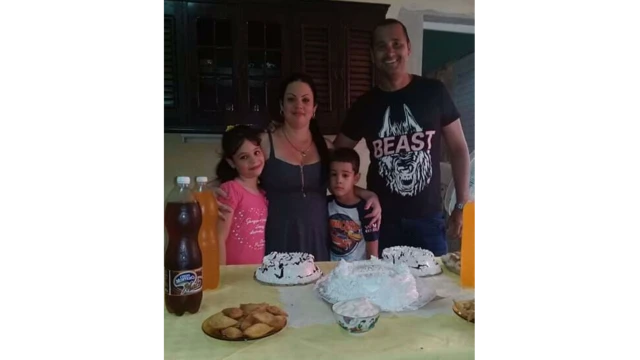 O casal e os dois filhos posam para foto em frente a mesa de aniversário