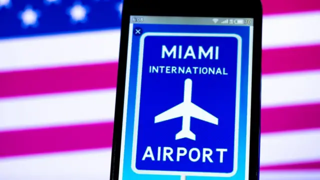 Placa do aeroporto internacional de Miami, com bandeira dos EUA no fundo