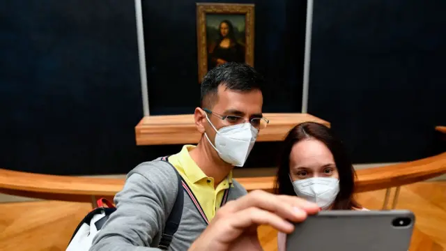 Pessoas tirando selfie em frente à a Mona Lisa no Museu do Louvre