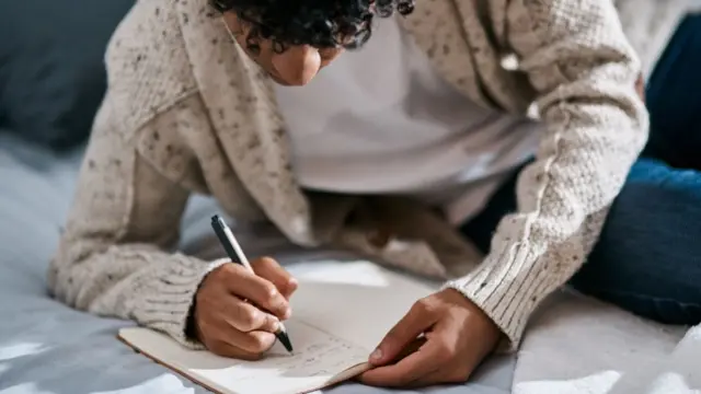 Homem escrevendo em um caderno