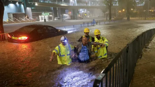 Drainage workers assisting a driver stranded due to flooding