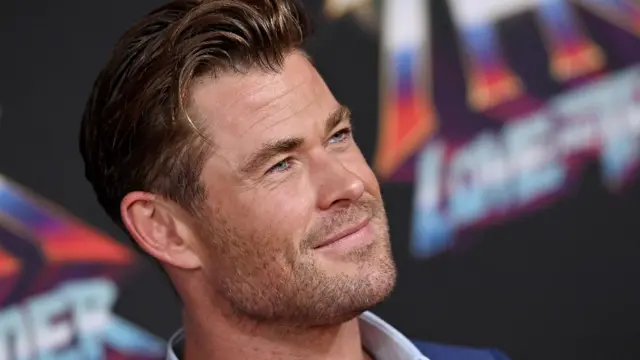 Chris Hemsworth de perfil, sorrindo contidamente