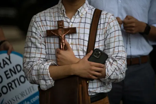 Um ativista antiaborto segura um crucifixo em frente a manifestantesdo lado de fora da prefeitura em Houston, Texas, em 14 de maio de 2022.