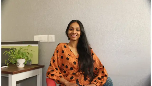 Pallavi sitting with a clear background behind her