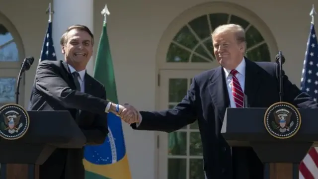 Bolsonaro e Trump apertam as mãos e sorriem em encontro no início do ano