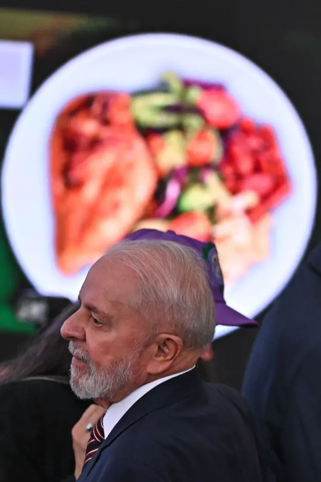 Lula de perfil, à frente da imagem de uma prato de comida